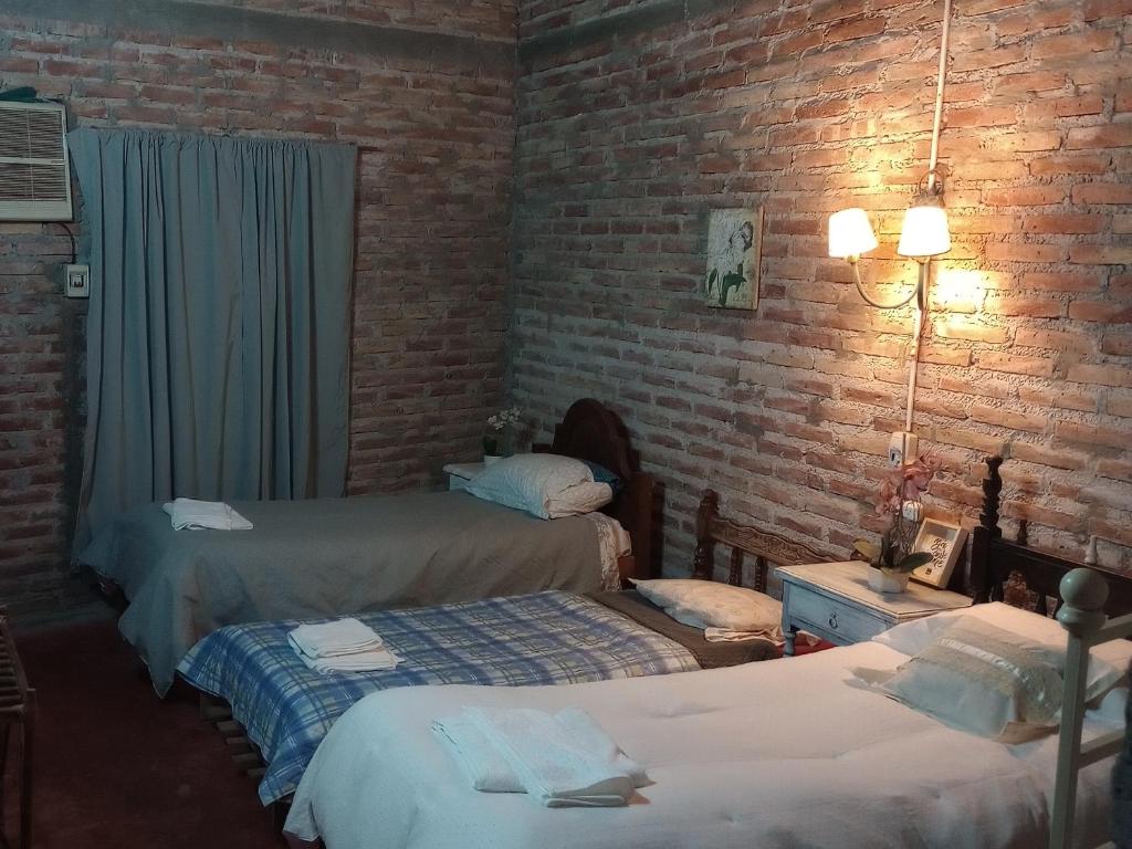 a bedroom with two beds and a brick wall at El quincho in Las Padercitas