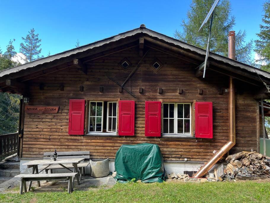 una baita di tronchi con persiane rosse e tavolo da picnic di Beautiful Swiss chalet with breathtaking views and a sauna 