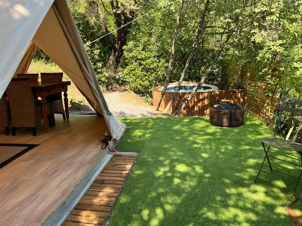 a backyard with a tent and a lawn with a table at Gîte Tipi avec sanitaires et Jacuzzi privatifs à Privas en Ardèche in Privas