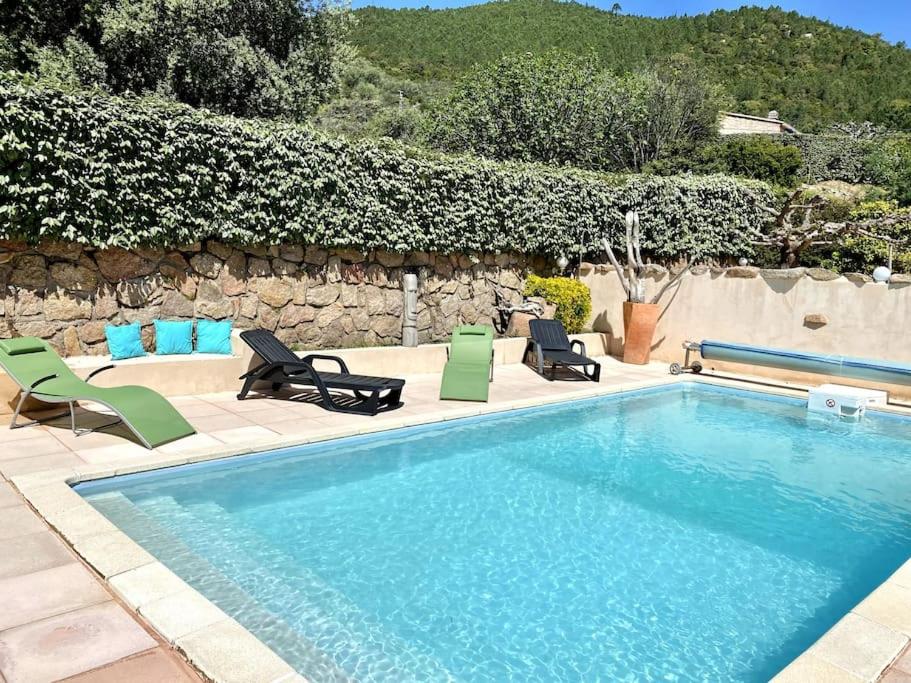 une piscine avec des chaises et un mur en pierre dans l'établissement Villa de charme Porto-Vecchio, Plage à 10 min, à San-Gavino-di-Carbini