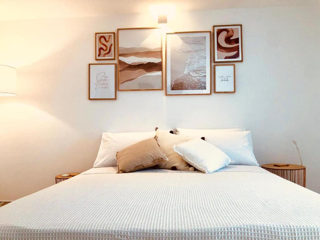1 dormitorio con 1 cama con 4 cuadros en la pared en Puerto Escondido, en Castro di Lecce