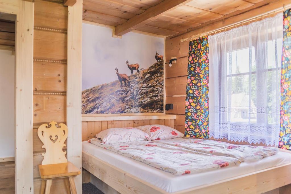 Cama en habitación de madera con ventana en Kiry 9 - pokoje i apartamenty, en Kościelisko