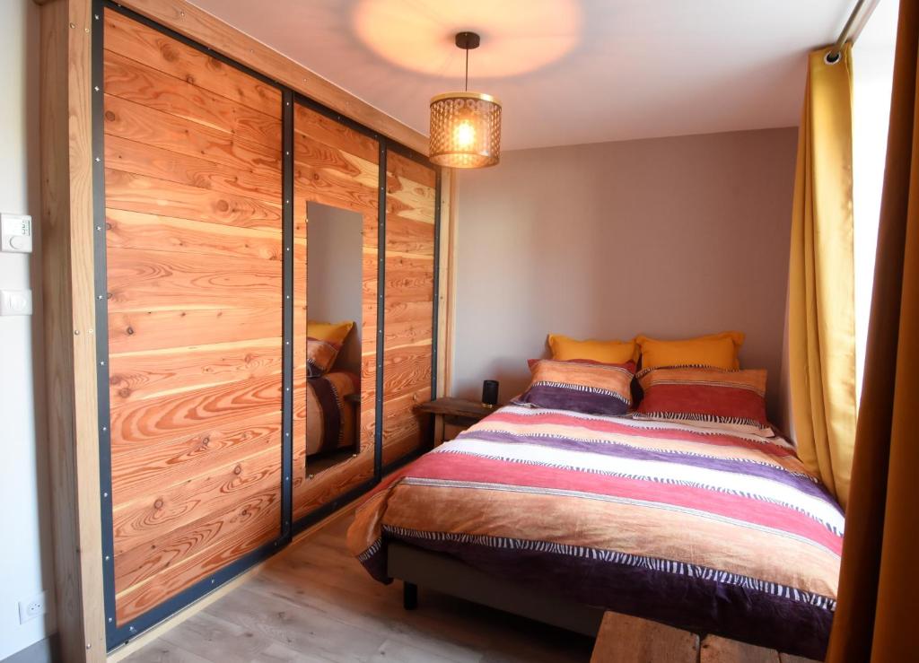 - une chambre avec un lit et un mur en bois dans l&#39;établissement La cure du Petit Doubs, à Rang