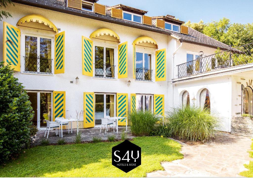 Una casa con persianas amarillas y azules. en Boutiquehotel Caravella Velden by S4Y, en Velden am Wörthersee