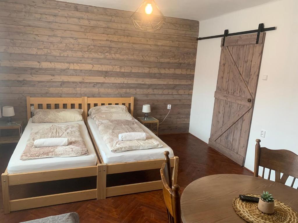 a bedroom with two beds and a wooden wall at Farma u Prokopů Humpolec in Humpolec