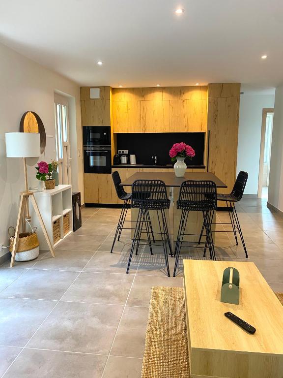 ein Wohnzimmer mit Stühlen und einem Tisch sowie eine Küche in der Unterkunft T3 Neuf, parking & garage privé, proche centre in Sarlat-la-Canéda