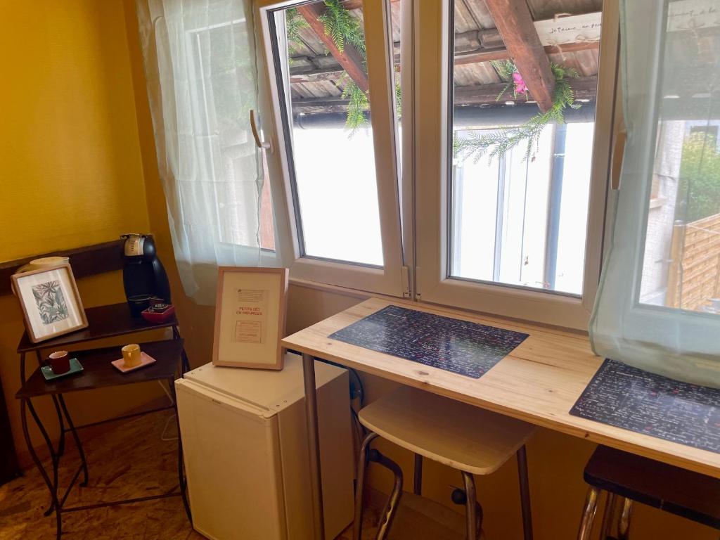 a room with a desk with two windows and a table at SousmonToi in Illkirch-Graffenstaden