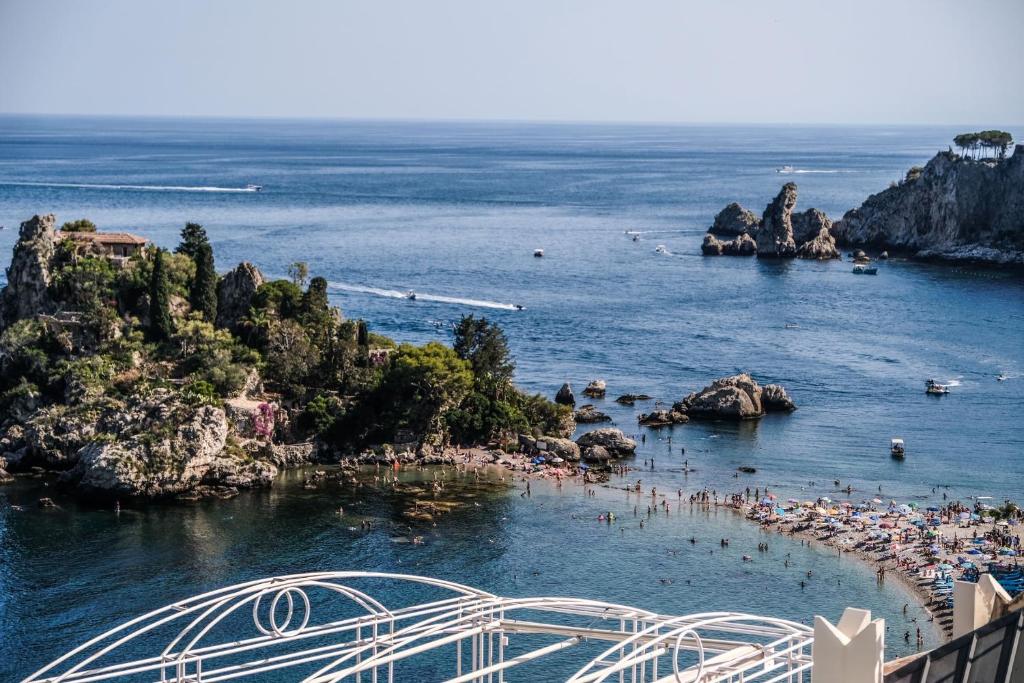 a beach with a bunch of people in the water at Isola Bella Luxury View in Taormina
