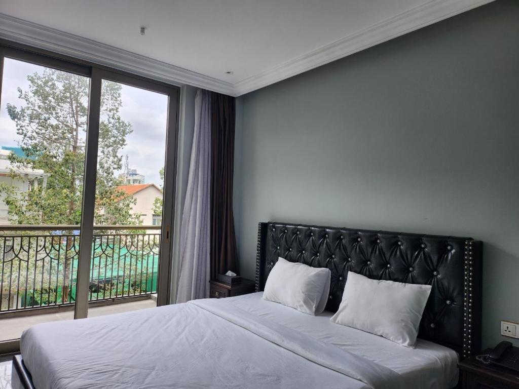 a bedroom with a bed and a large window at Feliz Hotel Binh Duong in Thu Dau Mot