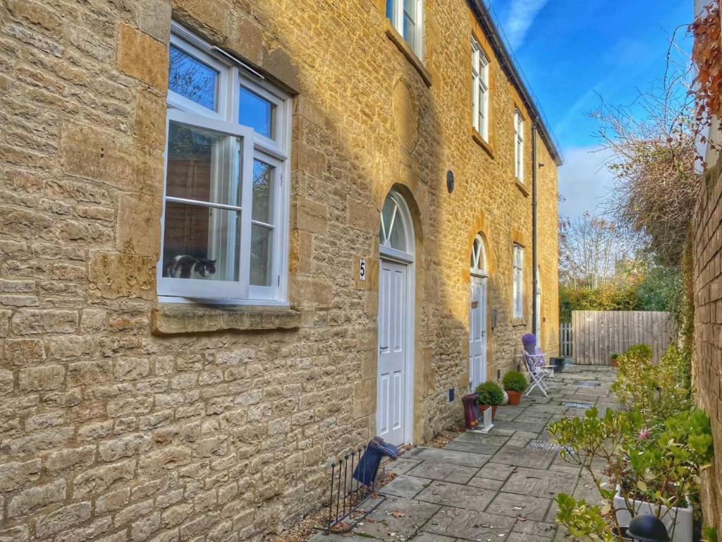 a yellow brick house with a white door and window at Cotswold Chapel, sleeps up to 5 in kingsize beds in Chipping Norton