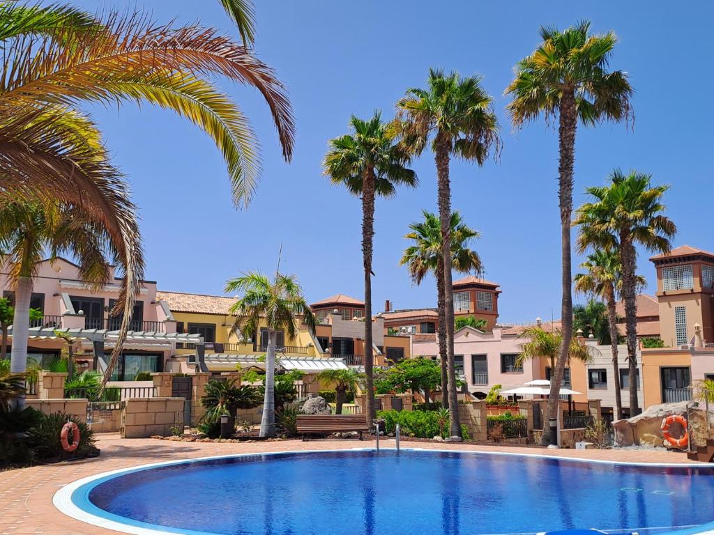 a pool with palm trees and buildings in the background at Modern Townhouse Ocean Front in Adeje