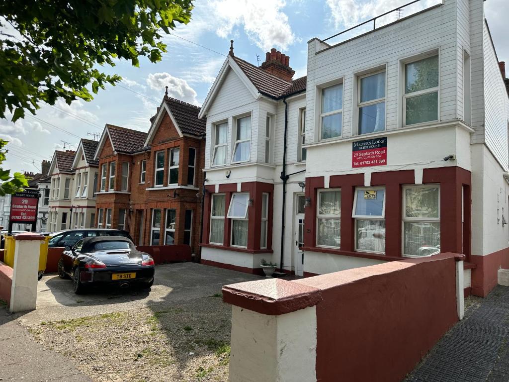 a row of houses on a street with a car at Malvern Lodge Guest House- Close to Beach, Train Station & Southend Airport in Southend-on-Sea