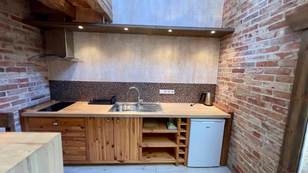 uma cozinha com um lavatório e uma parede de tijolos em Kapteinis Āķis apartamenti em Ulmale