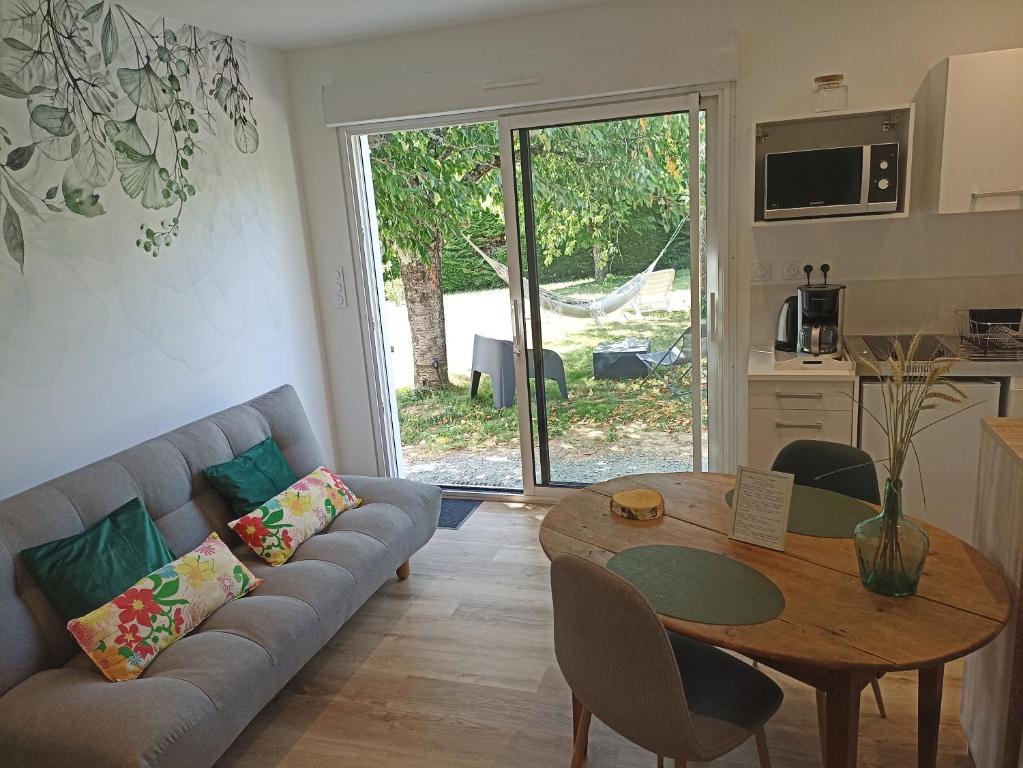 ein Wohnzimmer mit einem Sofa und einem Tisch in der Unterkunft L'Anne'xe champêtre d'Alex, calme, proche ville in Fontenay-le-Comte