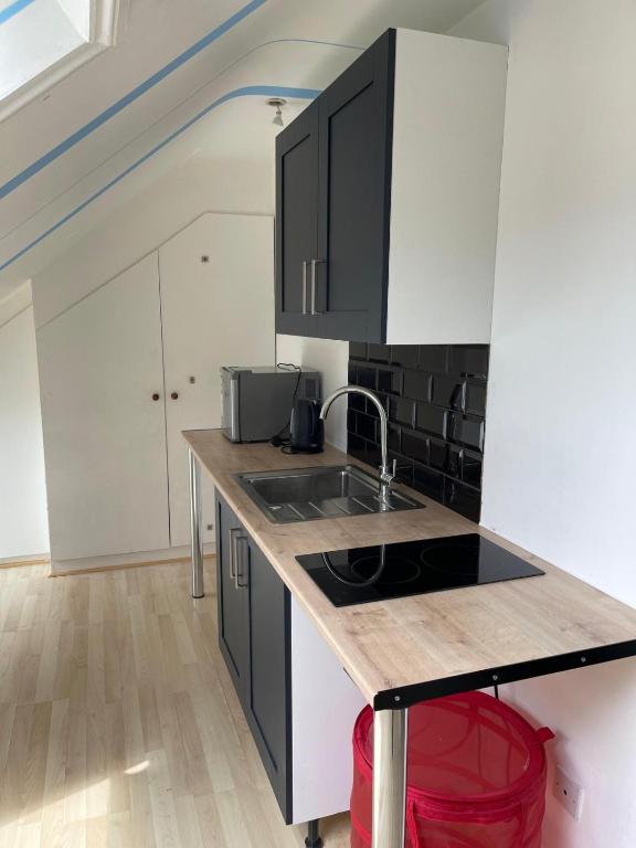 a kitchen with black and white cabinets and a sink at 2nd floor Enfield town studio flat in Enfield