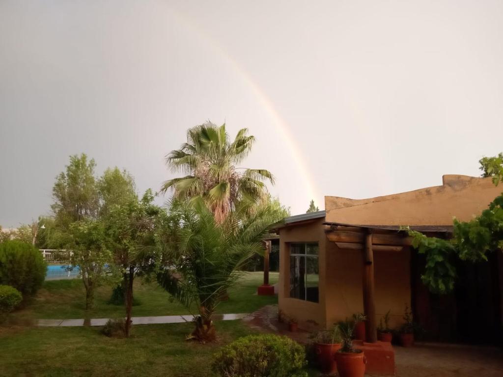 un arco iris sobre una casa con una palmera en Casa Rural en San Rafael con pileta, en San Rafael