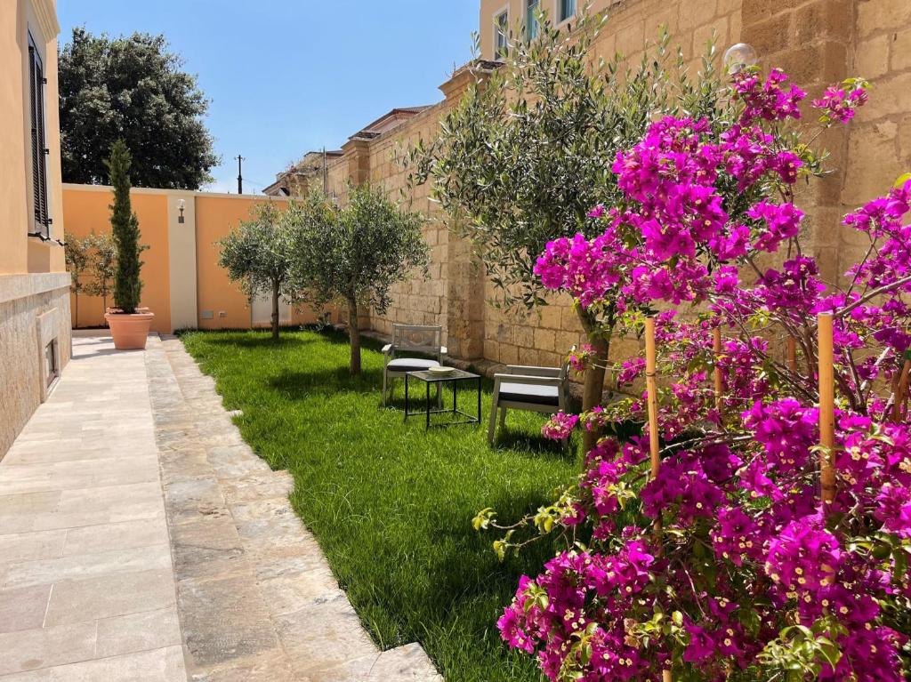 un giardino con fiori viola accanto a un edificio di Palazzo Pitagora a Taranto