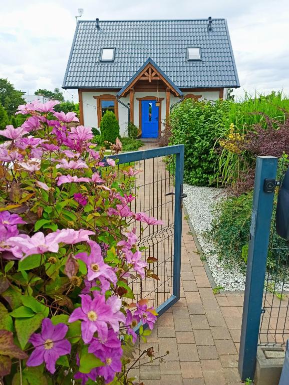 a gate in front of a house with purple flowers at Żuławska Osada in Trutnowy