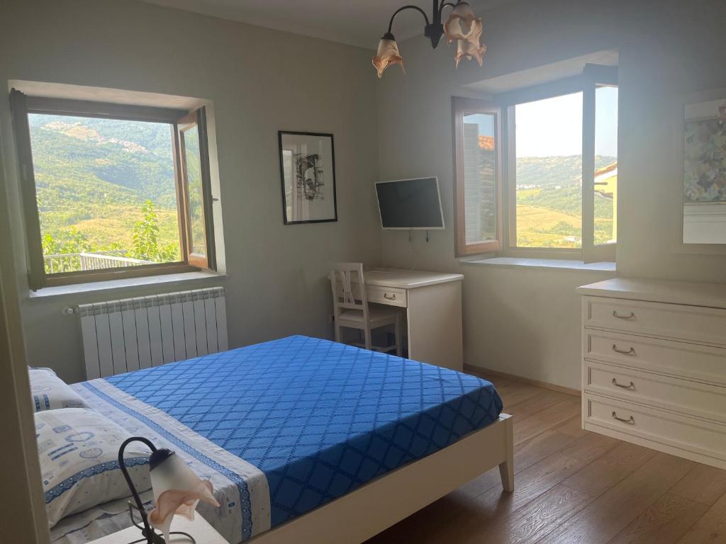 a bedroom with a bed and a desk and two windows at Green Deluxe Apartment “La locanda del Borgo” in San Donato di Ninea