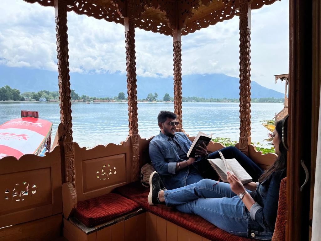 Ein Mann und eine Frau, die auf einem Boot sitzen und Bücher lesen in der Unterkunft New kolohai group of houseboats in Srinagar
