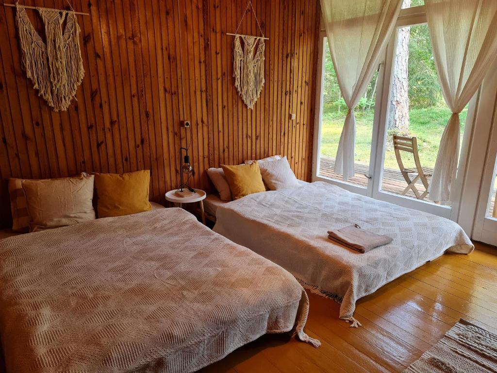 a bedroom with two beds and a large window at Viesuliškės Lakeside Glamping in Lakaja