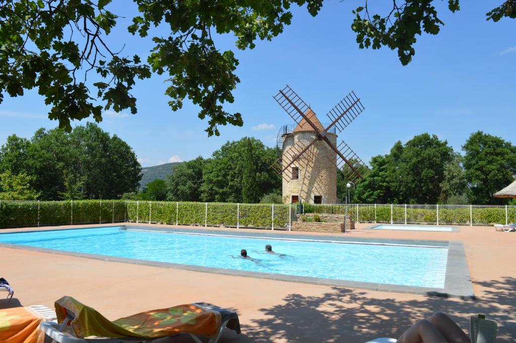 un molino de viento y una piscina con dos personas. en le moulin, en Vallon-Pont-dʼArc