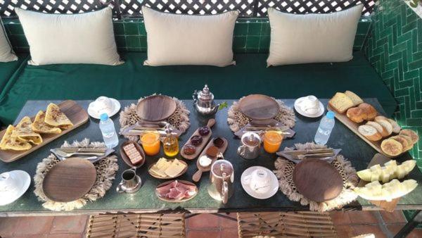 uma mesa cheia de comida e bebidas num sofá verde em EL BAHJA HOTELL em Marraquexe