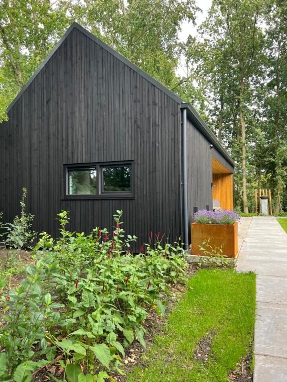 una casa negra con un jardín delante en It Skoft, en Siegerswoude