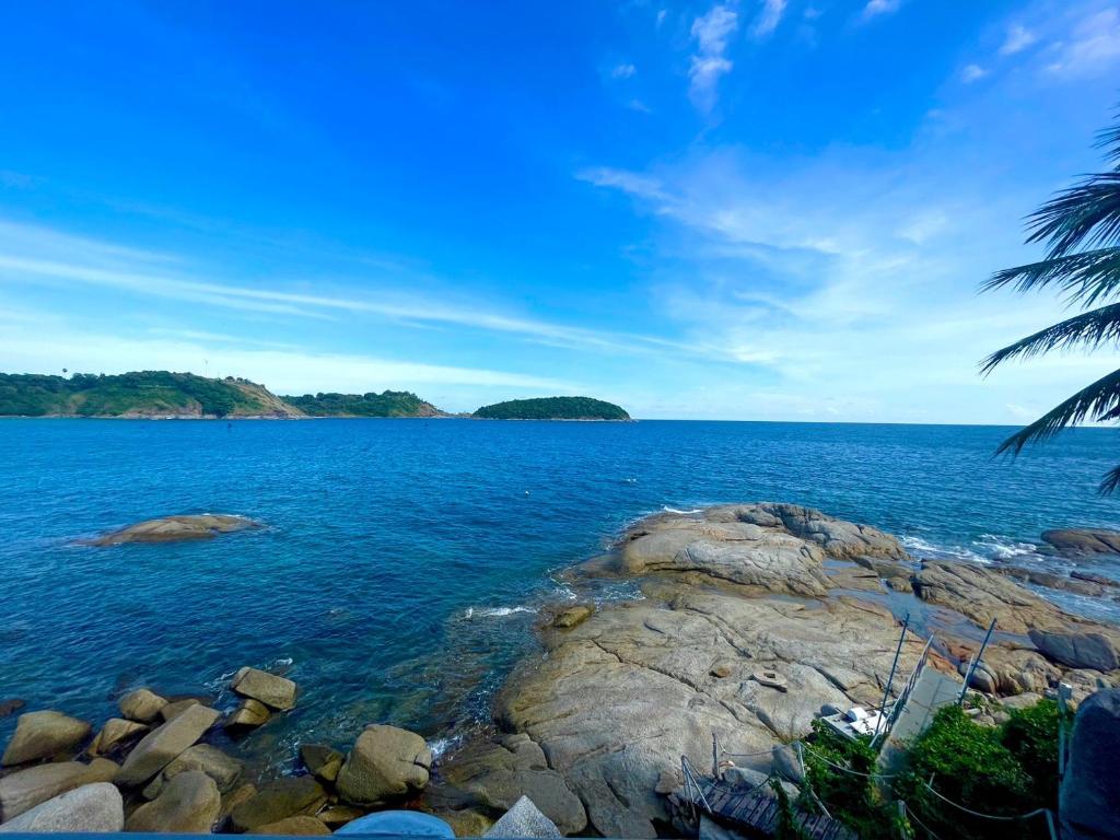 a view of a large body of water with rocks at Naiharn On The Rock Resort Phuket in Nai Harn Beach
