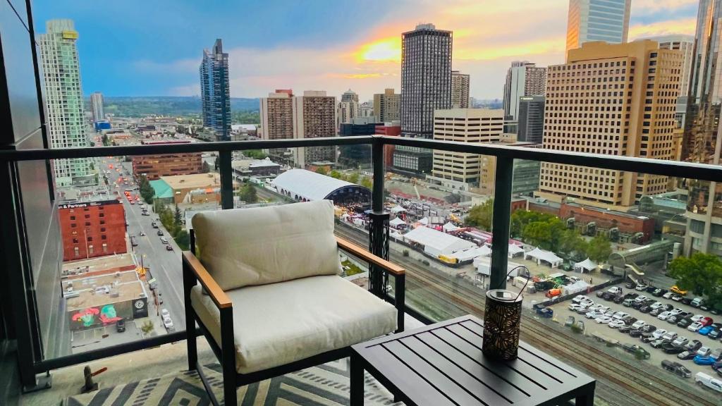 a chair on a balcony with a view of a city at LUXURY Downtown Sunset Getaway - Your Home Away From Home - Fully Stocked Kitchen, Gym, Balcony, FREE PARKING in Calgary