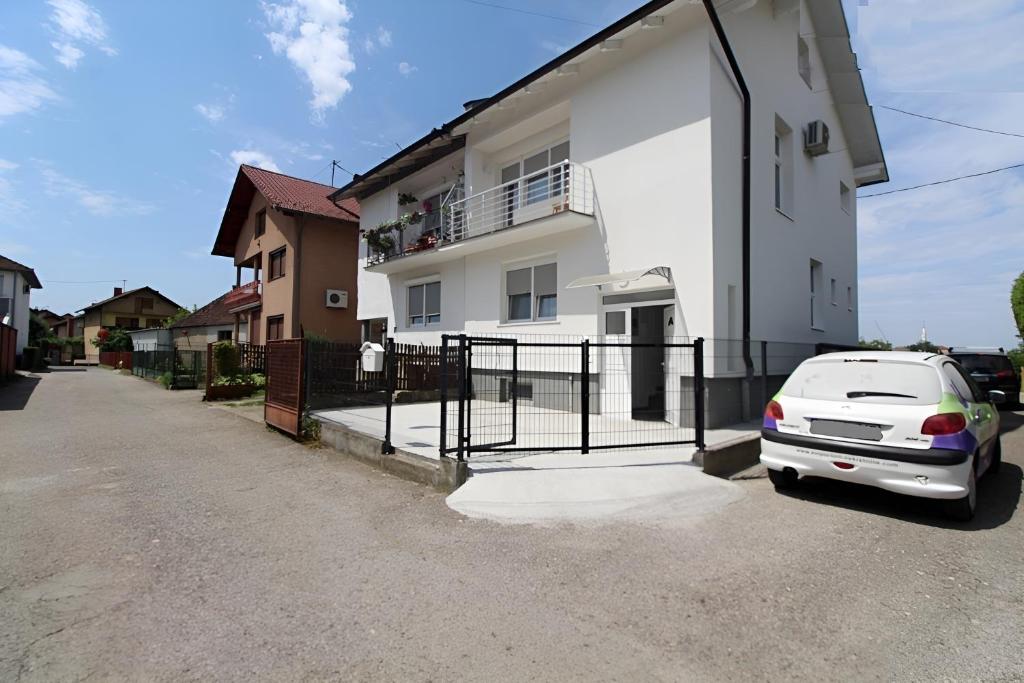 una macchina bianca parcheggiata di fronte a una casa bianca di Apartman SKY 4 a Brčko
