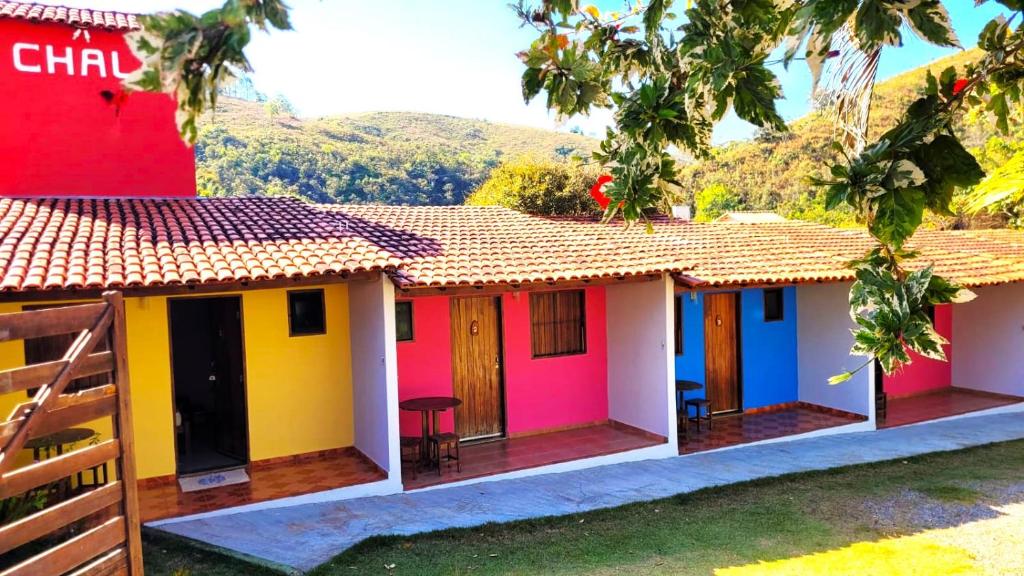 una fila de casas de campo coloridas con montañas en el fondo en Chalé da Vó en Vargem Bonita