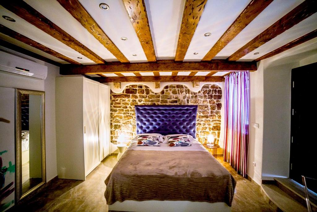 1 dormitorio con 1 cama grande y pared de piedra en Apartment Genius Loci, en Split