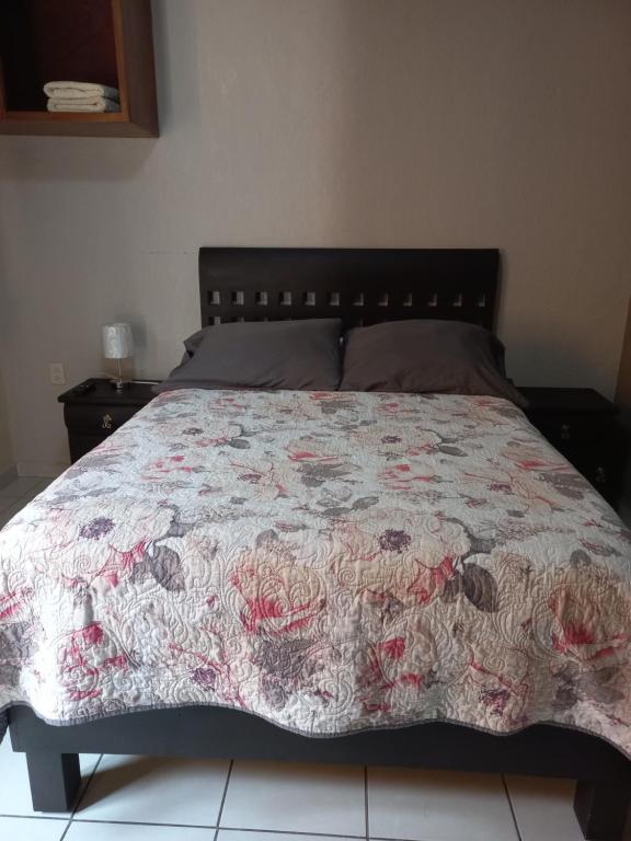1 dormitorio con 1 cama con colcha de flores en Agradable y cómodo departamento a 5 minutos del aeropuerto, en Ciudad de México