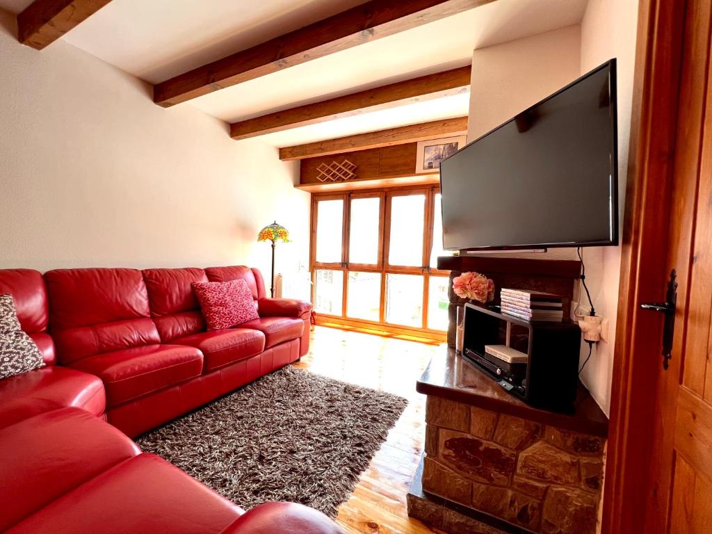 ein Wohnzimmer mit einem roten Sofa und einem Flachbild-TV in der Unterkunft El Raconet d'Espot in Espot