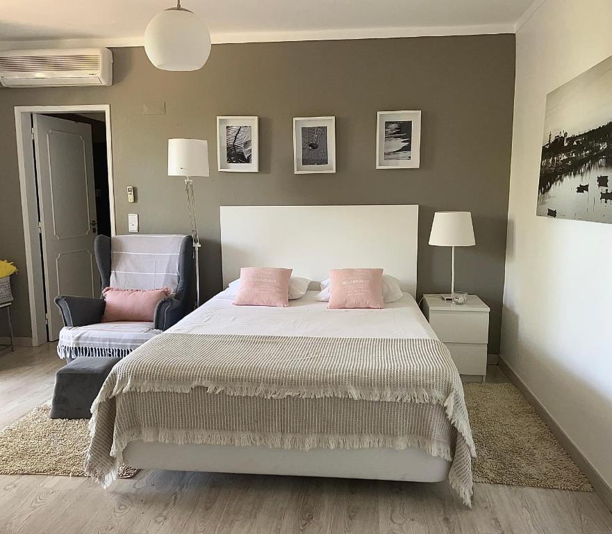 タヴィラにあるSweet Home Chill Out Studioのベッドルーム1室(ピンクの枕と椅子付きのベッド1台付)