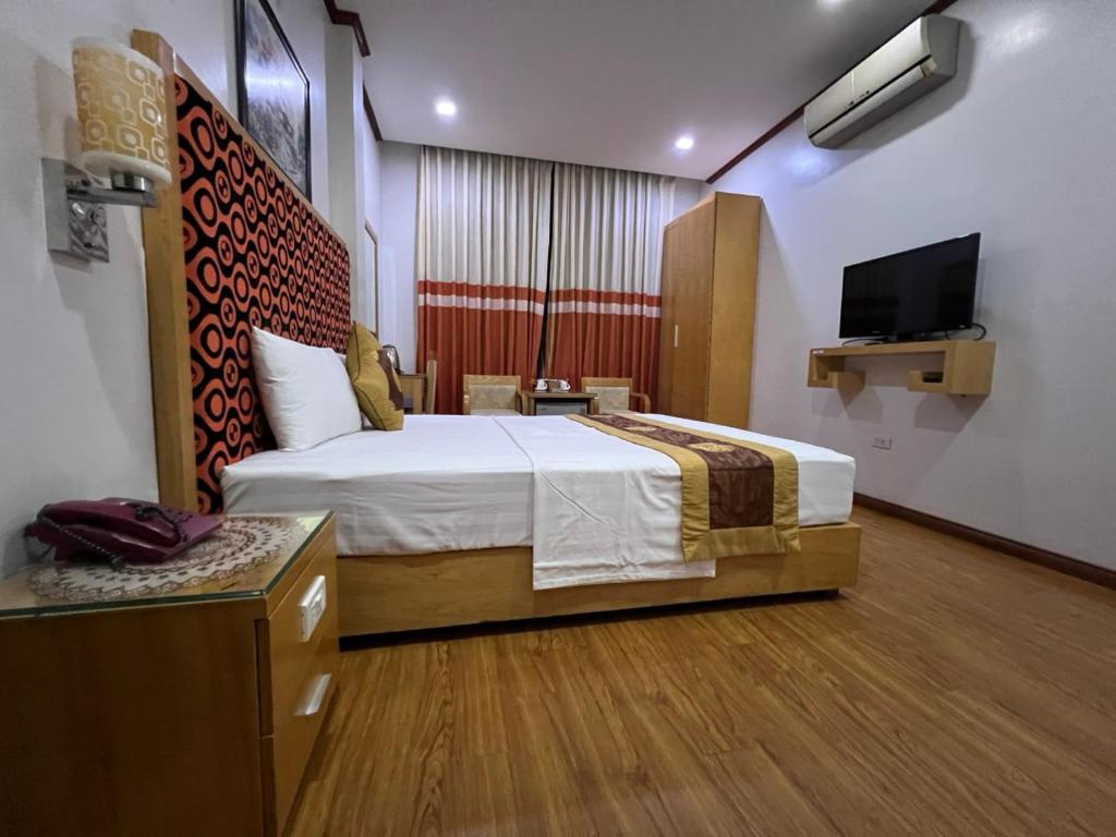 a bedroom with a bed and a flat screen tv at Khach sạn Vân Nam in Hanoi