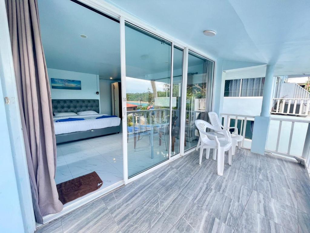 a room with a balcony with a bed and chairs at Naiharn On The Rock Resort Phuket in Nai Harn Beach
