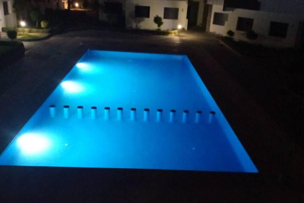 a swimming pool with blue lighting in a yard at night at Appt a 500 m de la plage in Douar Ourlali