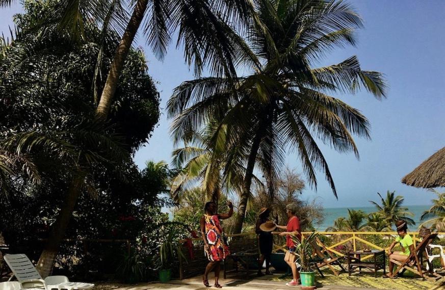 a group of people standing on a beach with palm trees at ECOLODGE SAFARI in Cap Skirring