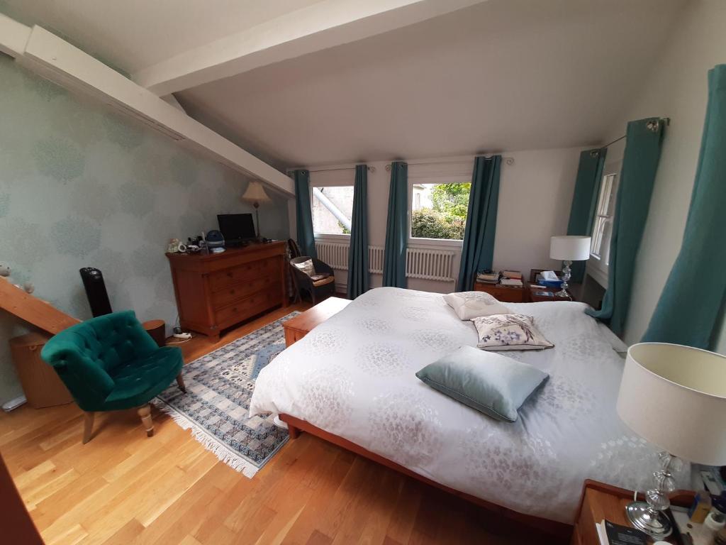 a bedroom with a large bed and a green chair at Loft en duplex 270 m2 &amp; Jardin patio terrasse sauna in Chaville