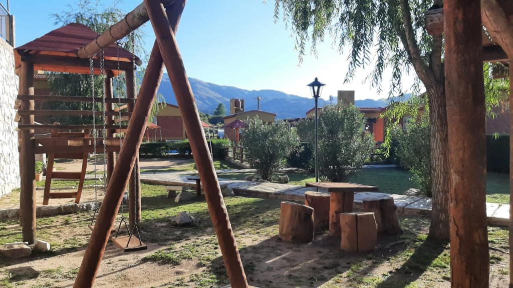 a swing set in a park with a tree at Cabañas Gemas del Lago in Potrero de los Funes