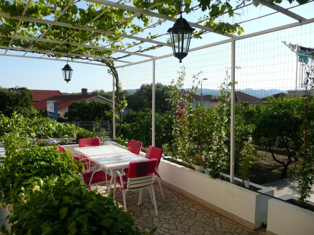 a patio with a white table and red chairs at Apartment Nima Orebic in Orebić