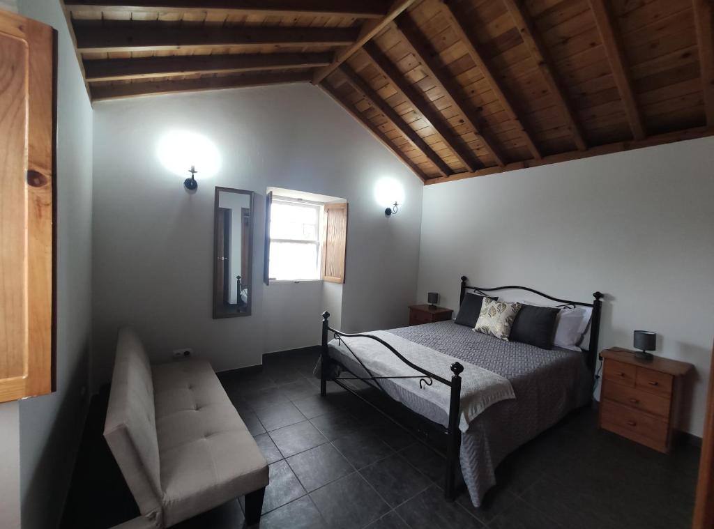 1 dormitorio con 1 cama, 1 silla y 1 ventana en Casa das Hortênsias en Horta