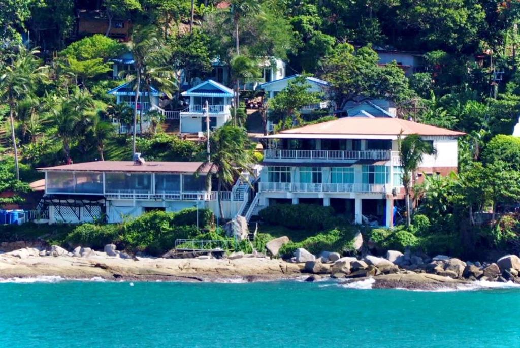 a large house on the shore of the ocean at Naiharn On The Rock Resort Phuket in Nai Harn Beach