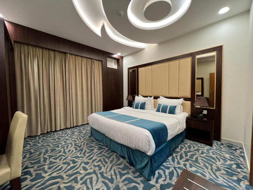 Pokój hotelowy z dużym łóżkiem i krzesłem w obiekcie هدوء الليالي للأجنحة الفندقية w mieście Chamis Muszajt