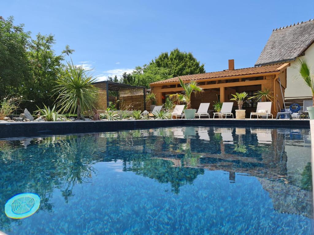 a swimming pool with chairs and a house at La villa du lac d'orient in Géraudot