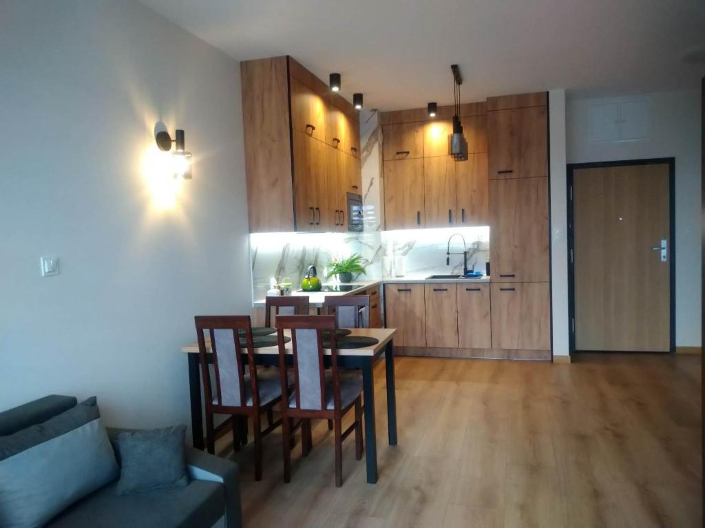 a living room with a table and chairs and a kitchen at Uniejów Apartament in Uniejow