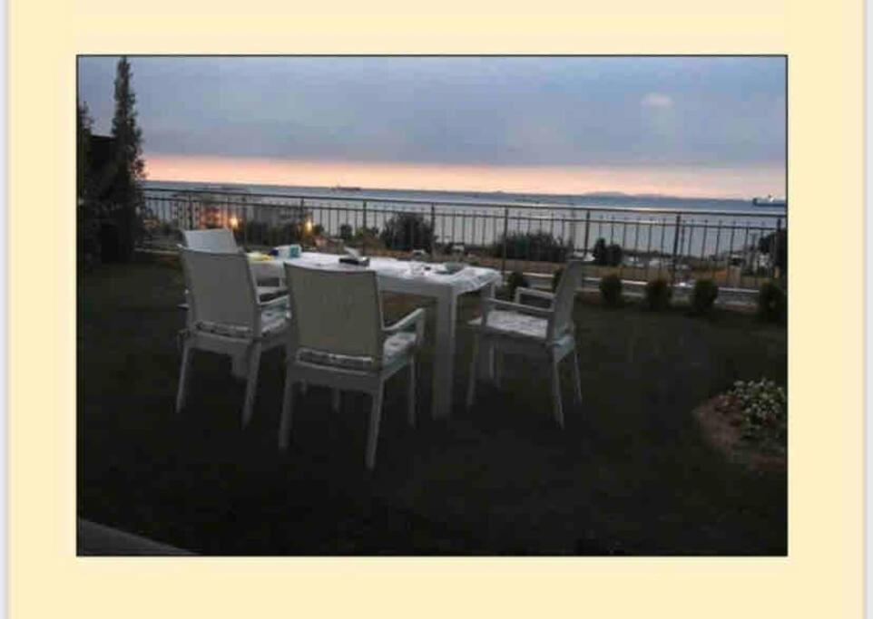 a table and chairs on a lawn with a view of the ocean at فيلا باطلالة بانورامية على البحر وقريبة من المركز in Yalova