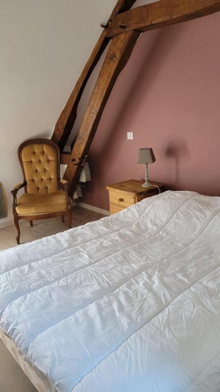 ein Schlafzimmer mit einem weißen Bett und einem Stuhl in der Unterkunft Maison proche Zoo de Beauval in Poulaines